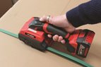 Friction weld strapping tool being demonstrated on a cardboard box with green strapping